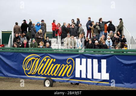 Racegoers are seen beyond William Hill signage at Kempton Park Racecourse Stock Photo