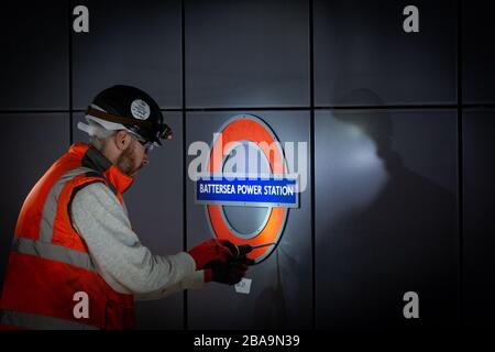 An engineer installs a roundel on the platform at Battersea Power Station, London Underground station Stock Photo