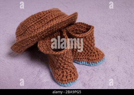 Knitted hat and boots. Knitted shoes and clothes. Booties for babies. Stock Photo