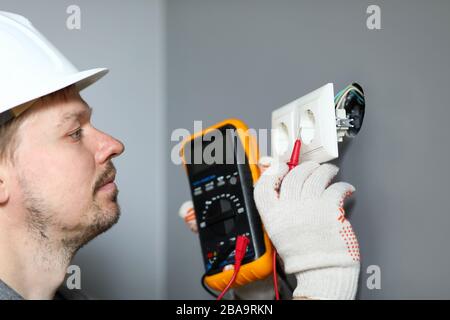 Electrician in helmet measures level electricity Stock Photo