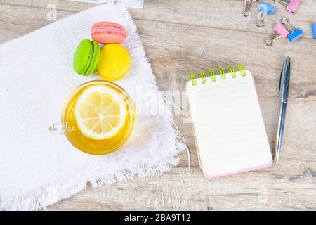 An open notebook with a silver pen, a cup of mint tea with lemon and multi-colored muffins stand next to it Stock Photo