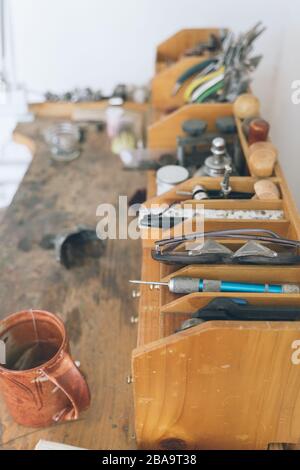 Detail of assorted tools used for making jewelery on wooden work bench Stock Photo