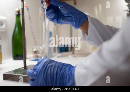 Close up of lab technician by placing a sample on beaker. Stock Photo