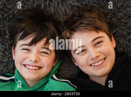 Looking down at the faces of two boys beside each other laughing. Stock Photo