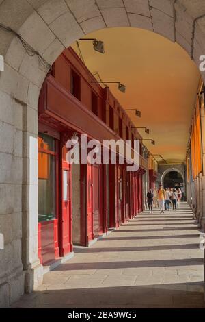 Plaza Mayor,Madrid,Spain;September 16 2018:Image from one of the arches of Plaza Mayor with people walking shopping in traditional shops of the city i Stock Photo