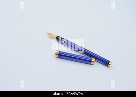 A blue and golden fountain Pen with its lid on white background Stock Photo