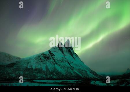 Otertinden peak in Norway, under the northern lights Beautiful mountains through Arctic Norway, with the Auroras dancing on top.  Lyngen Alps Scandina Stock Photo