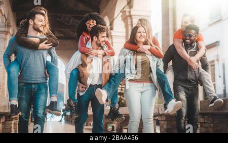 Happy people piggybacking. Community of multi racial friends having fun together. Integration of mixed culture students smiling and having fun togethe Stock Photo
