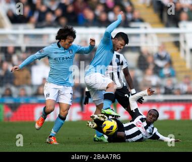 Newcastle United's Vernon Anita (right) and Manchester City's Sergio Aguero (centre) battle for the ball Stock Photo