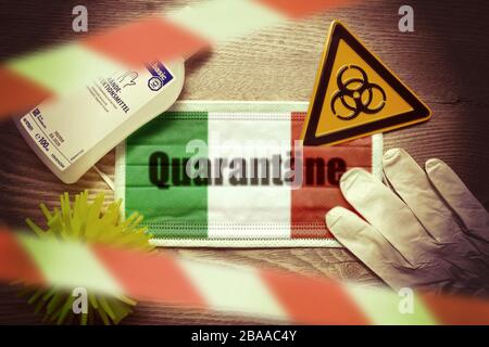 PHOTOMONTAGE, mask in Italian national colours with stroke quarantine, stop tape, biology danger sign, protective gloves and disinfectants on a table, Stock Photo