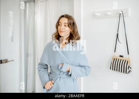 Young woman wearing outwear in the hallway, getting ready to leave the apartment Stock Photo