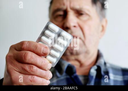 Coronavirus treatment and prevention, elderly man with white pills in blister packs. Concept of medical prescription, cold and flu, Alzheimer disease Stock Photo