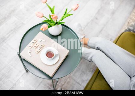 Flowers, books and cup of coffee on a round table indoors, top view. Work at home and cozy home atmosphere concept Stock Photo