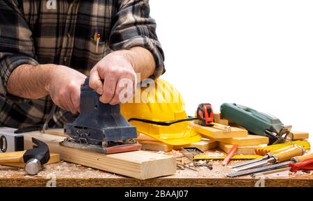 Close-up. Carpenter with the electric sander smoothes a wooden board. Construction industry. Isolated on a white background. Stock Photo