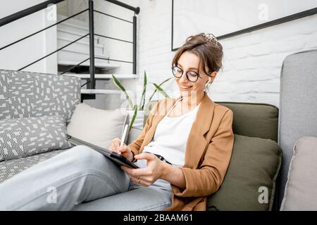 Portrait of a young creative woman as a web designer or artist, working on a digital tablet at home. Concept of a freelance and creative work online Stock Photo