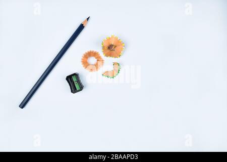 Black pencil sharpener beside a dark blue pencil crayon and some pencil shavings before a white background Stock Photo