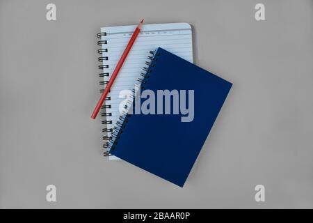 two diaries before a paper background with a red pencil crayon top of one of them Stock Photo