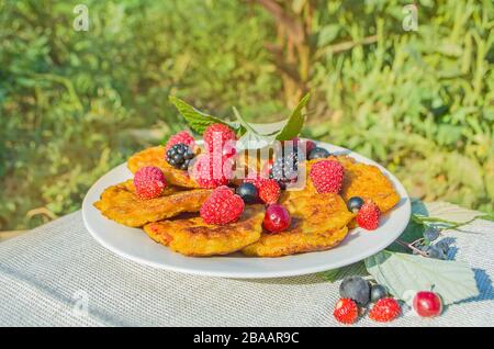 Curd fritters with raspberries, blackberries, currants, cherries and strawberries Stock Photo