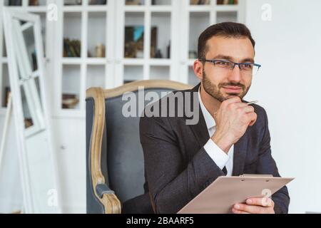 Dreamy young dark-haired man holding a clipboard Stock Photo