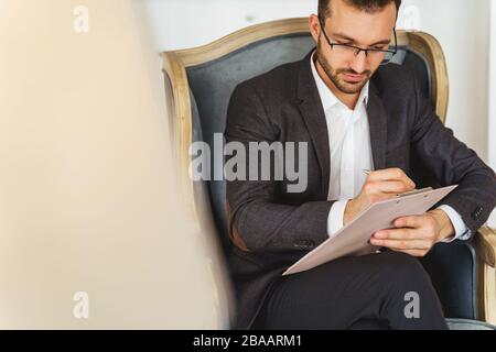 Serious short-haired male sitting in an armchair Stock Photo
