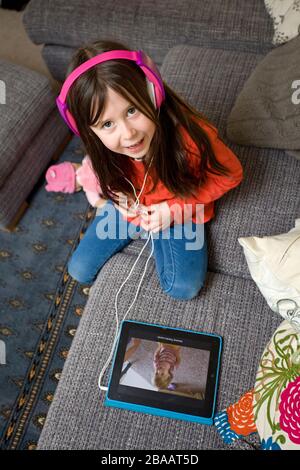 young girl watching the iPad wear headphones Stock Photo