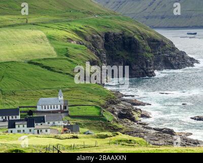 Faroe Islands, Viðoy, Viðareiði, view on the church and part of the town. In the background cliffs and ocean. Stock Photo