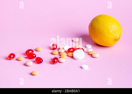 Lemon and scattered multi-colored pills on a pink background Stock Photo