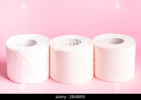 Three rolls of white toilet paper close-up on a pink background  Stock Photo