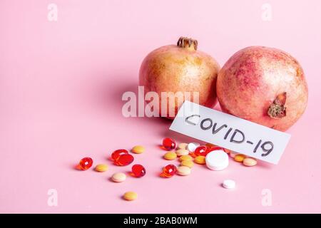 Two Garnet and scattered multi-colored pills on a pink background Stock Photo