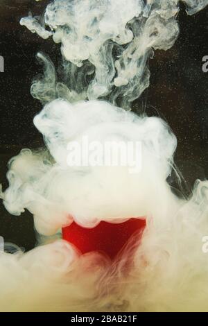 White stains on a black background with bubbles in a red cup. Abstract black-white natural background. Stock Photo