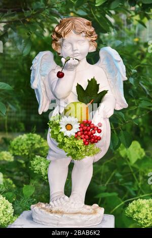 Sculpture of an angel in the garden holding flowers and fruit Stock Photo