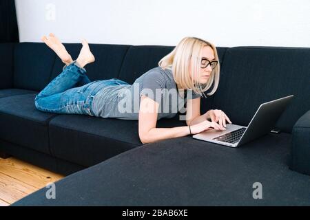Distance online learning education and work. Female Person working office work remotely from home. Casual woman with eye glasses using laptop in huis Stock Photo