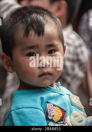 Shanghai, China - May 4, 2010: Closeup of face of young boy toddler with azure shirt, looking seriously straight into the camera. Stock Photo