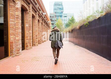 Bearded man walking across pathway holding a take away coffee Stock Photo