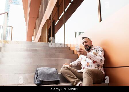 Handsome young man dressed casually spending time outdoors with mobile Stock Photo