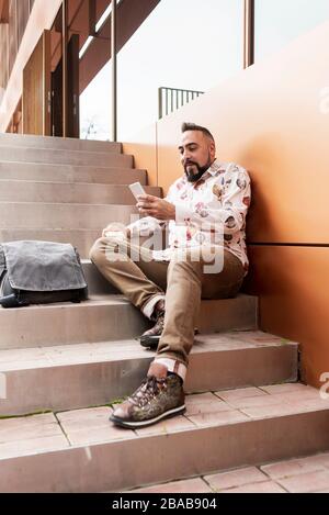 Handsome young man dressed casually spending time outdoors with mobile Stock Photo