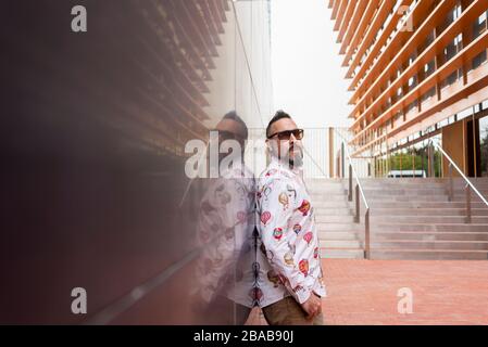 Side view of a bearded male leaning on a office building wall Stock Photo