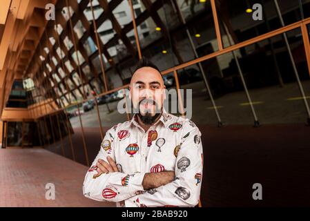 Bearded man with crossed arms while standing against office building. Stock Photo