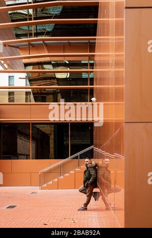 Side view of a bearded male leaning on a office building wall Stock Photo