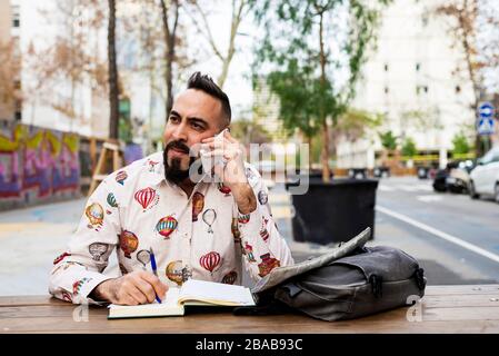 Young bearded businessman sitting at table,using mobile phone Stock Photo