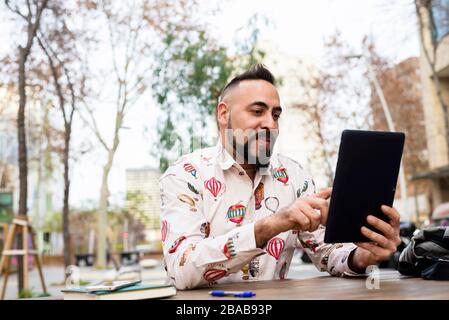 Young bearded businessman sitting at table,using tablet computer Stock Photo