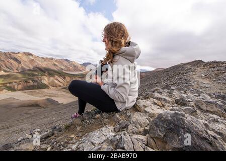 Woman smiling sitting with camera in the wind, in Landmannalaugar Stock Photo