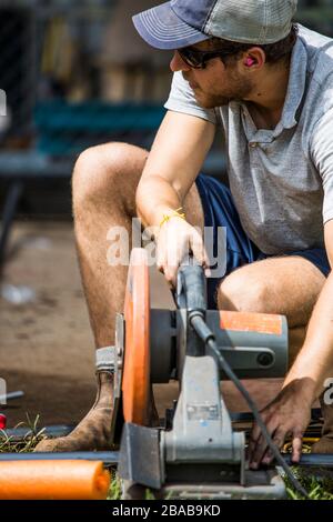 Close-up of skilled worker using chop saw to cut steel. Stock Photo