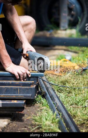 Worker uses angle grinder to cut steel on construction site. Stock Photo