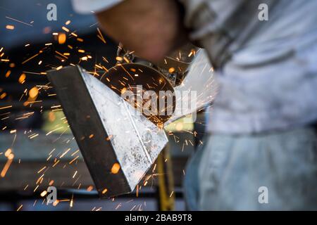 Close-up of worker using angle grinder in a factory Stock Photo