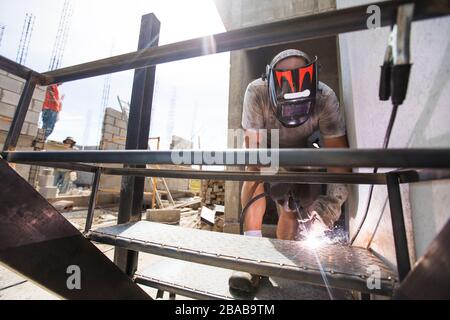 construction site worker welding staircase at building site. Stock Photo