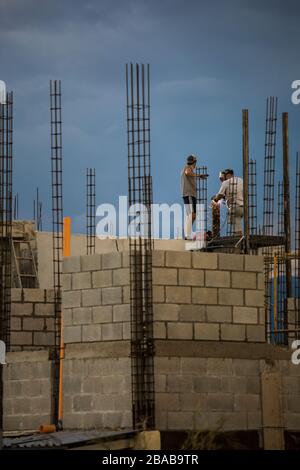 Two construction workers work or rooftop, welding metal railing. Stock Photo