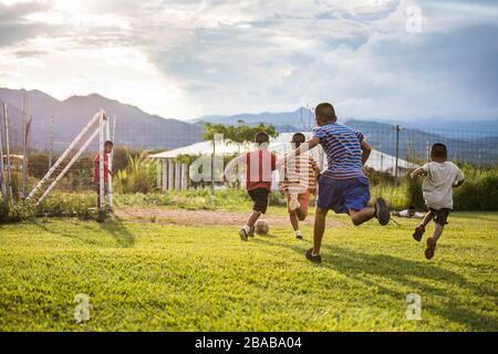 Group of friends playing soccer on grass field before sunset.