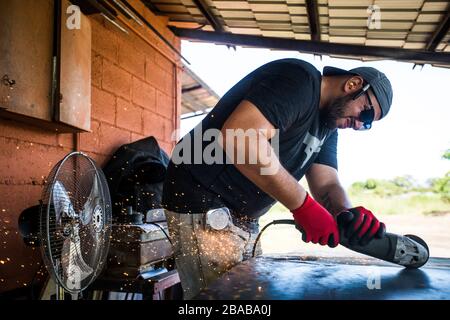 Worker concentrating, using angle grinder to cut steel. Stock Photo