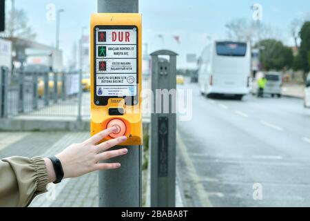 Istanbul, Turkey - February 11, 2020: A female hand presses on the transition push button for pedestrians. Pedestrian crossing with a device for contr Stock Photo